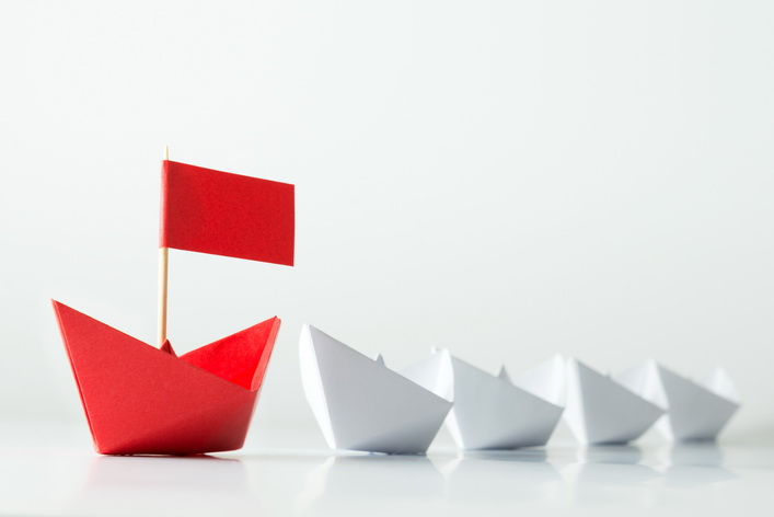 Leadership concept with red paper ship leading among white