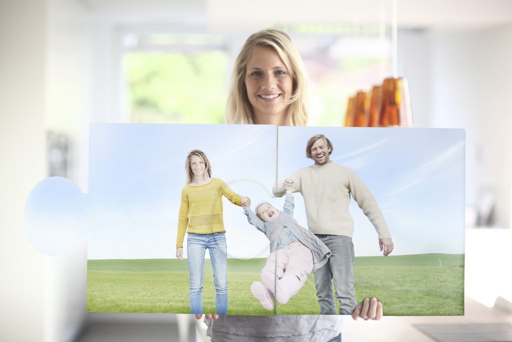 Mid adult woman holding large jigsaw pieces of family