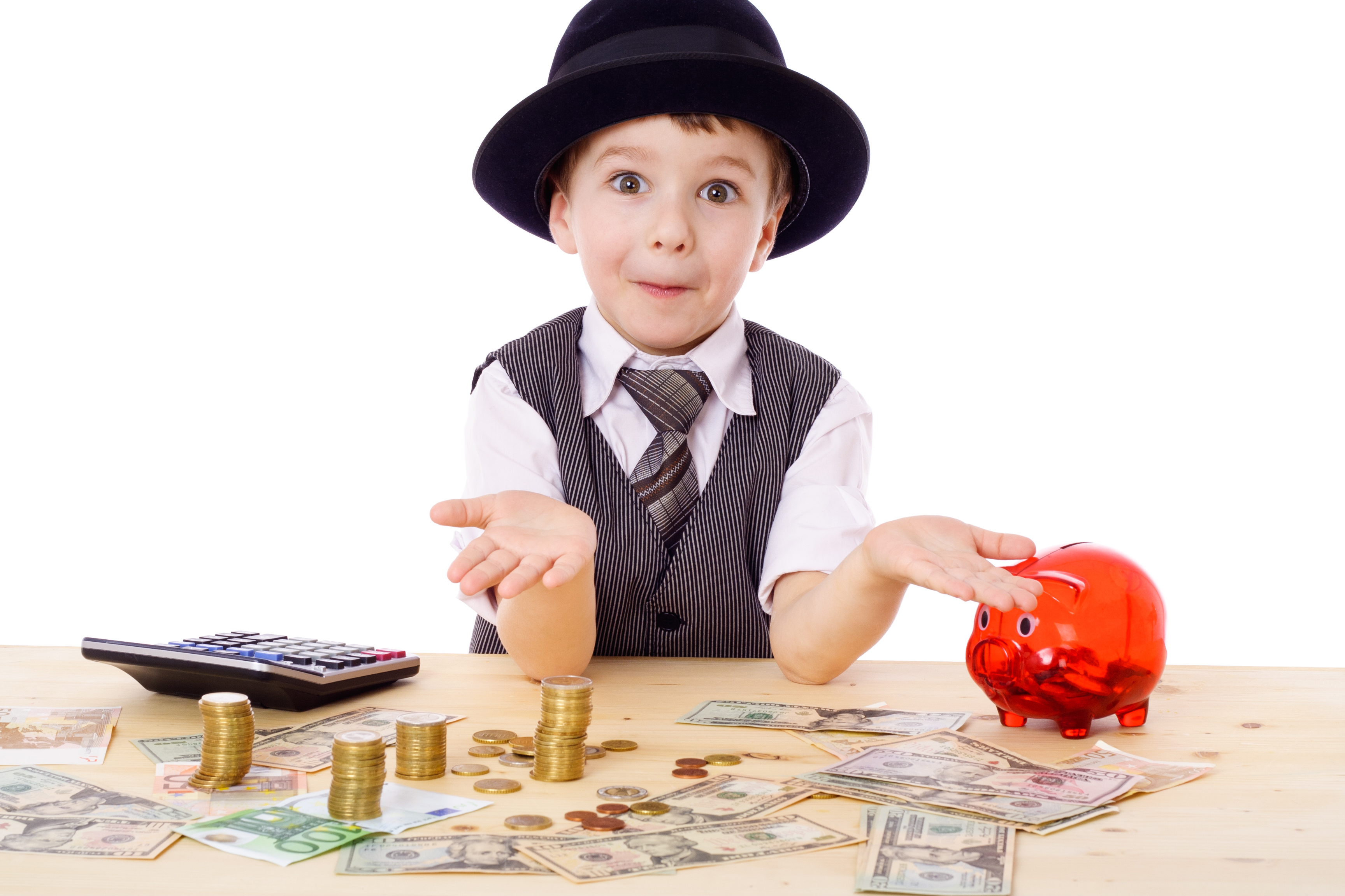 Sly boy in black hat with empty hands at the table with pile of money, isolated on white